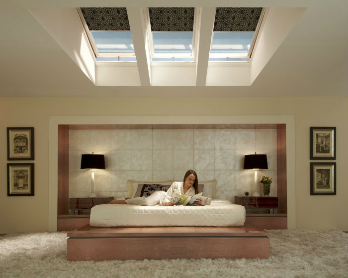 Kobieta w łóżku w sypialni czyta książkę przy lampach.